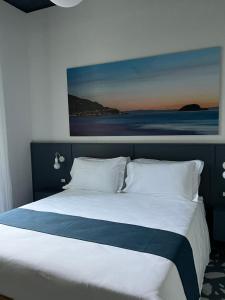 a bedroom with a large bed with a painting on the wall at Alaxia Luxury Apartments in Alassio