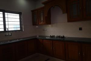 a kitchen with wooden cabinets and a sink and a window at Cliff Top View Guest House in New Mīrpur