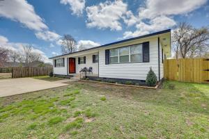 a white house with a red door in a yard at Cozy Duplex, Walk to Bentonville City Square! in Bentonville