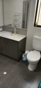 a bathroom with a white toilet and a sink at Near Train Station Transport Hub with Bicycle Locker in Perth