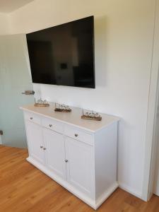 a white entertainment center with a flat screen tv on a wall at Moderne Wohnung mit Privatpool in Büsum