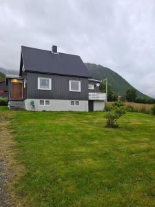a black and white house in a field of grass at Cozy house - Strønstad @the start of Lofoten in Strønstad