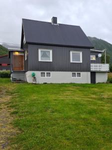 a black and white house with a green yard at Cozy house - Strønstad @the start of Lofoten in Strønstad