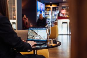 a person sitting at a table with a laptop and a glass at Peakture Hotel in Bucharest