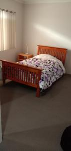 a bedroom with a wooden bed with a floral bedspread at Near Train Station Transport Hub with Bicycle Locker in Perth