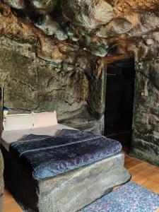 a room with a bed in a stone cave at Rai’s Coorg Cave House in Madikeri