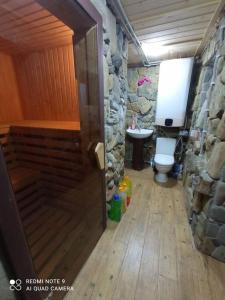 uma casa de banho com um WC e uma parede de pedra em Велика Дзен Хата em Dzembronia