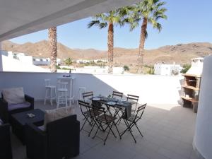 a patio with a table and chairs and palm trees at Apartamento Viento Del Sur in Las Negras
