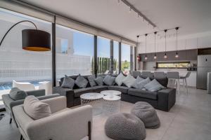 ein Wohnzimmer mit Sofas und Stühlen sowie eine Küche in der Unterkunft SunnyVillas: 3BR New Villa☆Private Pool in Pernera - White Swan in Protaras