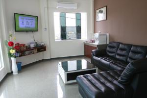 a living room with a leather couch and a tv at Alor Villa in Malacca