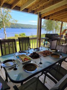 Rivière-RougeにあるSheldon Cozy on Lake Cottage with Private Jacuzziの青いテーブル(食べ物とワイングラス付)