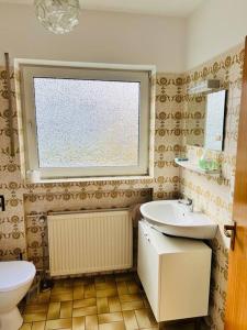 uma casa de banho com um lavatório, um WC e uma janela. em Ferienwohnung in Rheinnähe em Rheinbreitbach