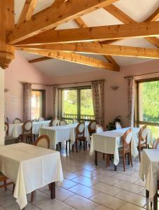 a restaurant with white tables and chairs and windows at Le Catinat Fleuri in Guillestre