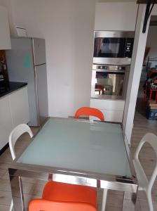 a kitchen with a glass table and two orange chairs at Casa Medea in Piombino