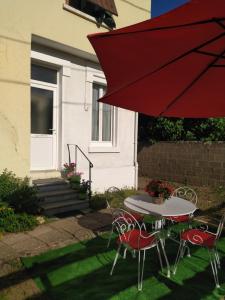 een terrastafel en stoelen met een rode parasol bij Warm and Cosy in Nevers
