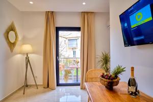 een woonkamer met een tafel, een tv en een raam bij Sunflower Suites Gouvia Corfu in Gouvia