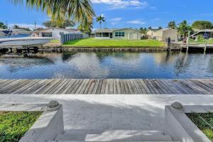 un muelle con un barco sobre un cuerpo de agua en Hot Tub! Roof Top! Firepit! Boat Dock!, en Fort Lauderdale