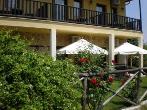 a building with white umbrellas and roses in a yard at Olympia Guesthouse in Vergina
