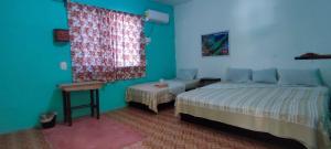 a bedroom with two beds and a window with a curtain at Villas del Carmen Hostal in Palenque