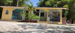 a yellow and green building with a palm tree in front at Villas del Carmen Hostal in Palenque