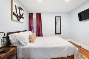 1 dormitorio con 1 cama blanca, escritorio y TV en Walk Downtown Ithaca Hiking Trails Watering Holes and Close to Cornell en Ithaca