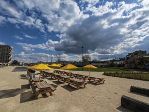eine Reihe von Picknicktischen mit gelben Sonnenschirmen in der Unterkunft Cosy Appartement T2 proche Paris in Ivry-sur-Seine
