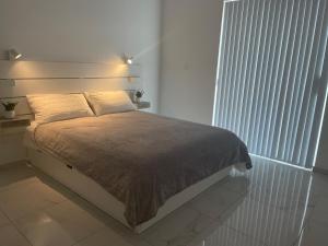 een bed in een witte kamer met een groot raam bij A52 - Apartment with Sea and Country Views in Mellieħa