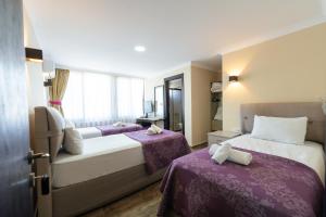 a hotel room with two beds with purple sheets at AKBÜK TAŞ OTEL in Akbük