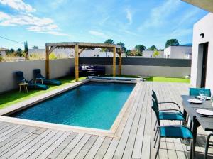 a swimming pool on a deck with a table and chairs at VILLA LE CORAIL ROUGE CORSE in Lecci