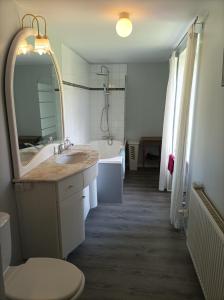 a bathroom with a sink and a mirror and a tub at La Petellerie, maison de campagne avec piscine pour un séjour détente in Moyon