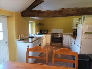 a kitchen with a white refrigerator and a table and chairs at La Petellerie, maison de campagne avec piscine pour un séjour détente in Moyon