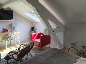 a attic room with a bed and a red chair at Manoir de Tireveste in Lesperon