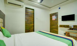 Treebo Trend Elvis Inn, Chandivali في مومباي: غرفة نوم بسرير ابيض وتلفزيون