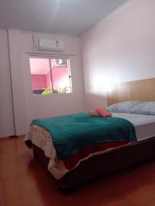 a bedroom with a bed with a green blanket at Apart Hotel Esperança in Ametista do Sul
