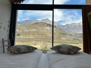 una camera con due letti e una grande finestra con montagne di Agritur La Corte dei Ciliegi a Trento