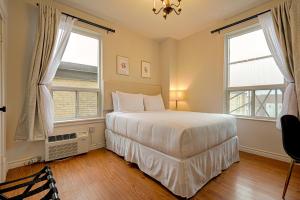 um quarto com uma cama branca e 2 janelas em The Windsor Hotel by Hoco Hotels Collection em Stratford