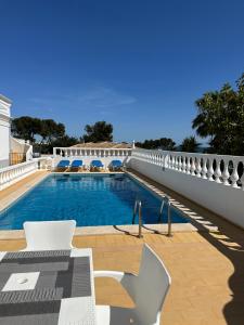 a swimming pool with chairs and a white fence at Vila Mar Central in Albufeira