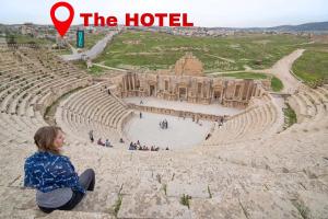 una mujer sentada en el borde de un anfiteatro en Panorama Jerash HOTEL (2), en Jerash