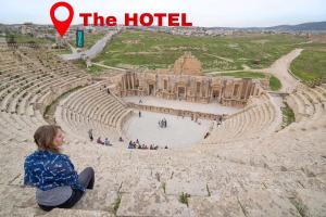 a woman sitting on the edge of an amphitheater at Panorama Jerash HOTEL (2) in Jerash