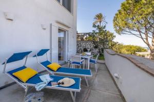 a balcony with blue and yellow chairs and a table at Casa Floriana Seaview in Capri