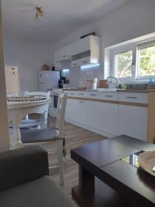 a kitchen with white cabinets and a table with chairs at Houlia home διαμέρισμα με δωρεάν χώρο στάθμευσης in Andros