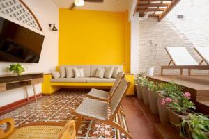 a living room with a couch and a yellow wall at 3CM-1 CASA COLONIAL DE 3 HABITACIONES CON PISCINA EN EL CORRALITO DE PIEDRA in Cartagena de Indias
