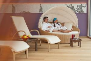 a man and a woman sitting in wicker chairs at Kreativ Hotel Landhaus Schweigl in Ultimo