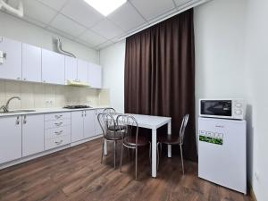 2-room Luxury Apartment on Sobornyi Avenue 192, by GrandHome في زاباروجيا: مطبخ مع دواليب بيضاء وطاولة وكراسي