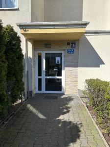 una puerta a un edificio con una acera y una puerta Sidx Sidx en SDH 3 Radzymin comfortable apartment near Warsaw, en Radzymin