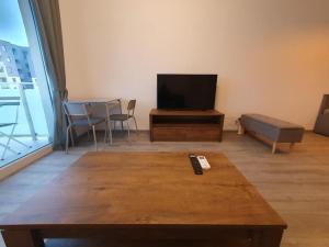 een woonkamer met een tafel en een flatscreen-tv bij New Luxury Flat Near City Center in Timişoara