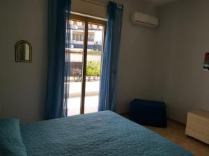 a bedroom with a blue bed and a window at Antigone Holiday House in Mondello