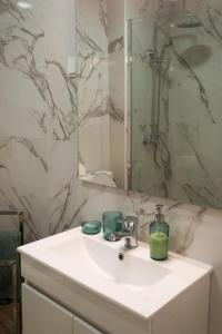 a white bathroom with a sink and a shower at Pópulo Mar in Ponta Delgada