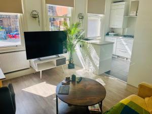 uma sala de estar com uma televisão de ecrã plano e uma mesa em Cozy apartment in Hampstead Heat em Londres