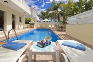 a pool with two chairs and a table with a glass of wine at Nissi Sapphire Villa in Ayia Napa